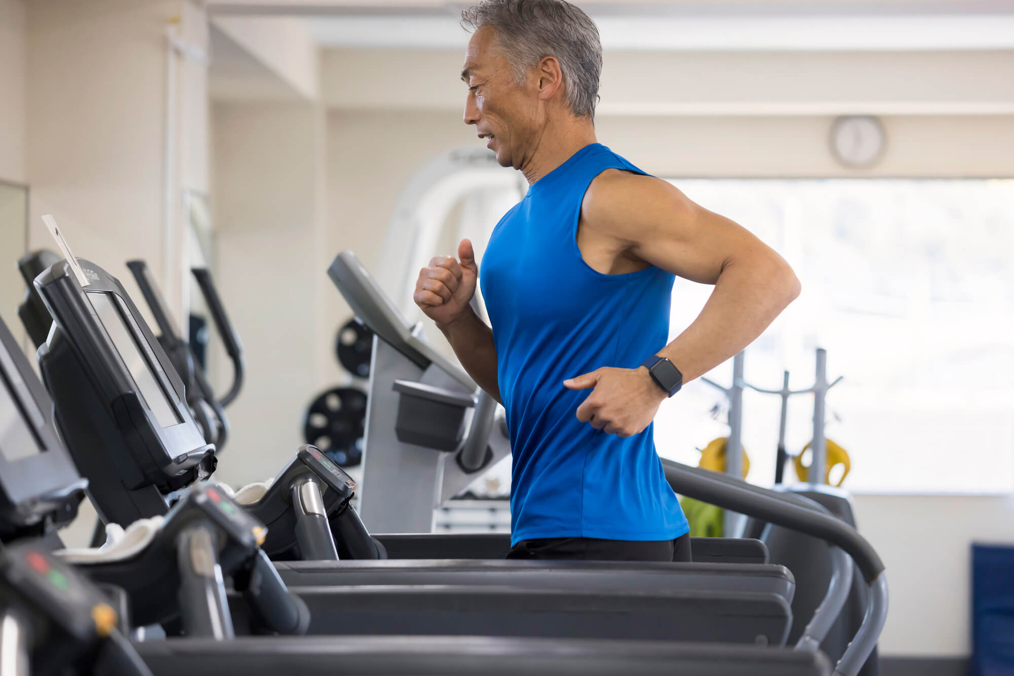 ランニングマシンで走るシニア男性