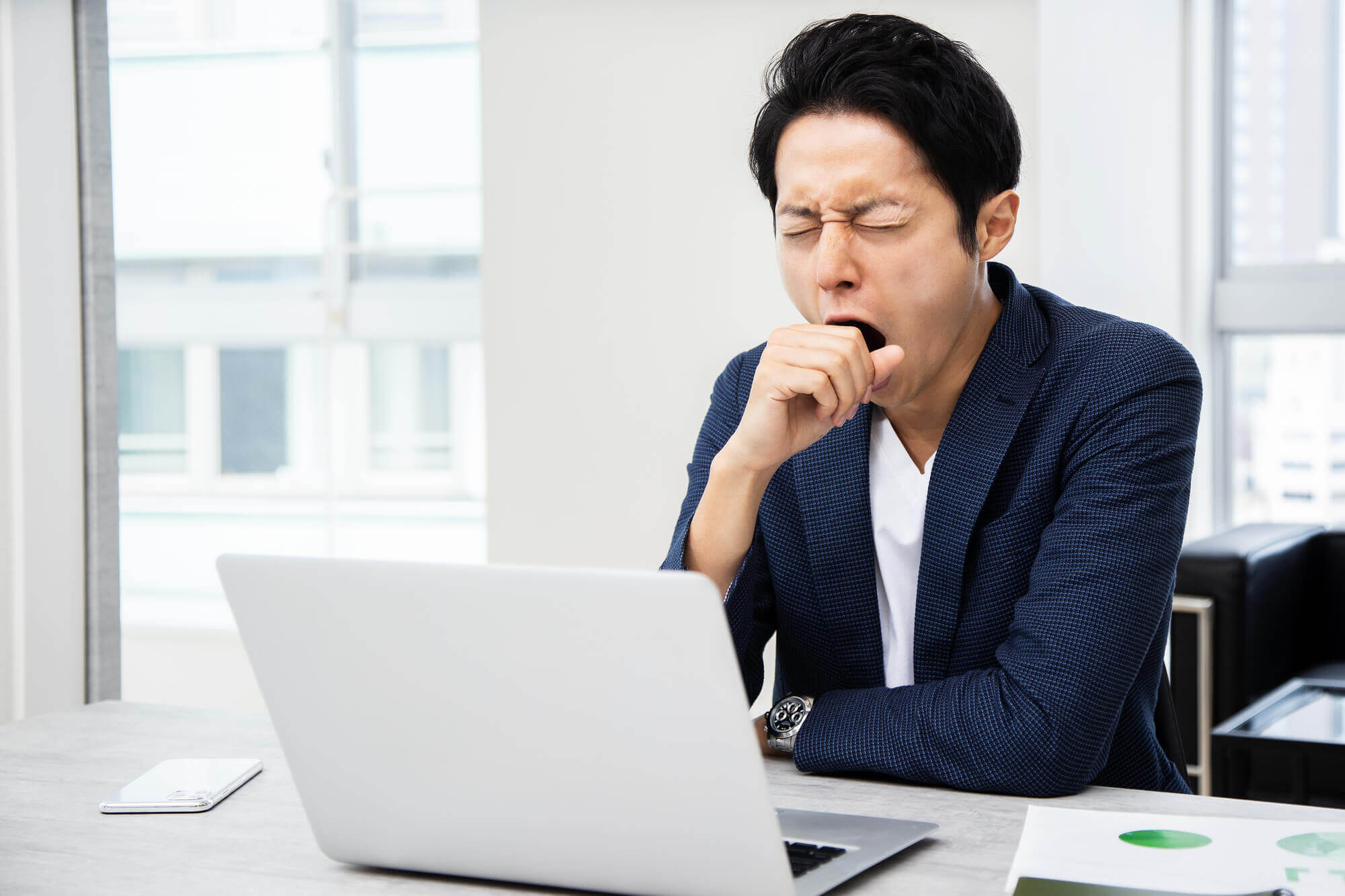 パソコンの前に座ってあくびをする男性