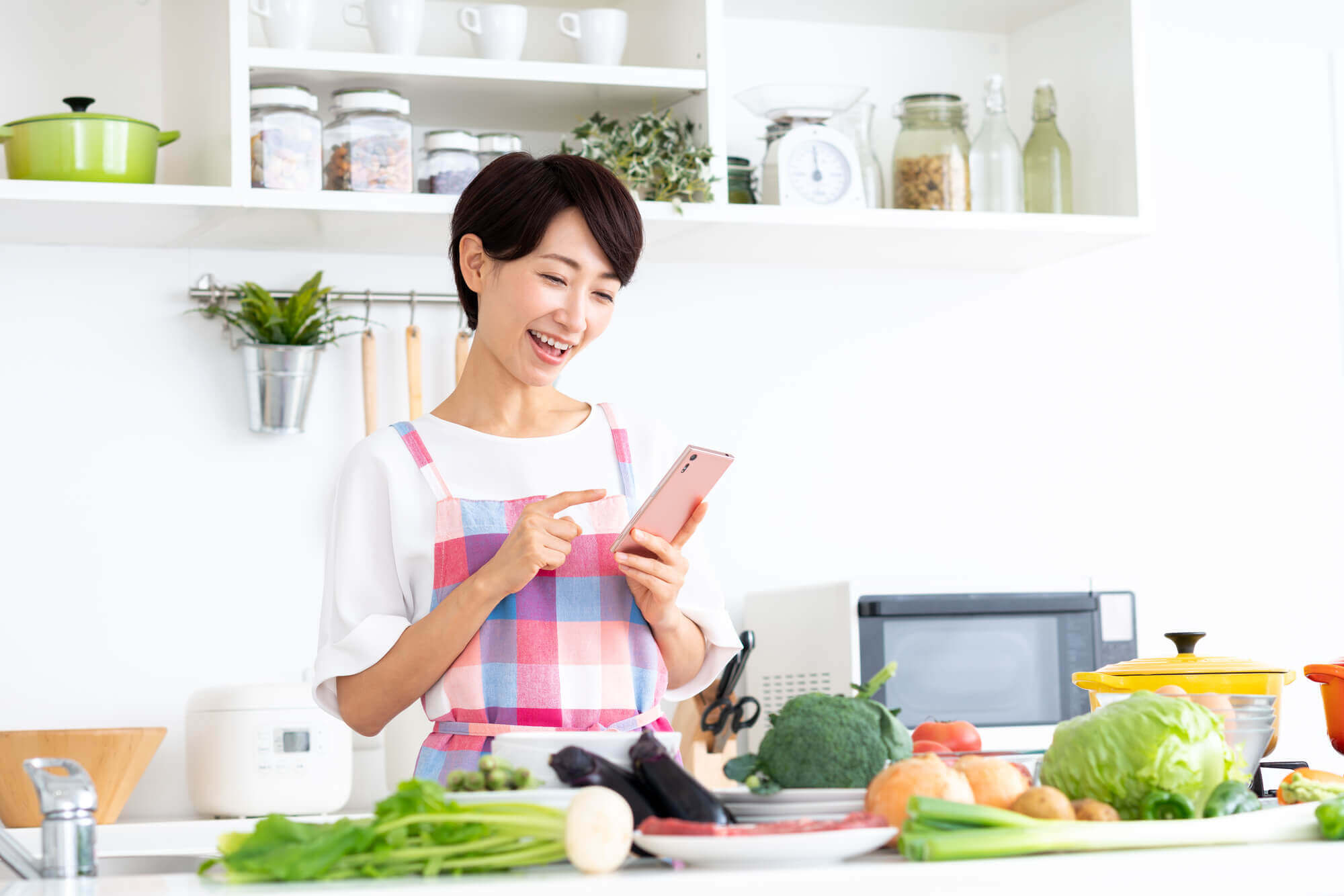 キッチンに立ってスマホを見ている女性