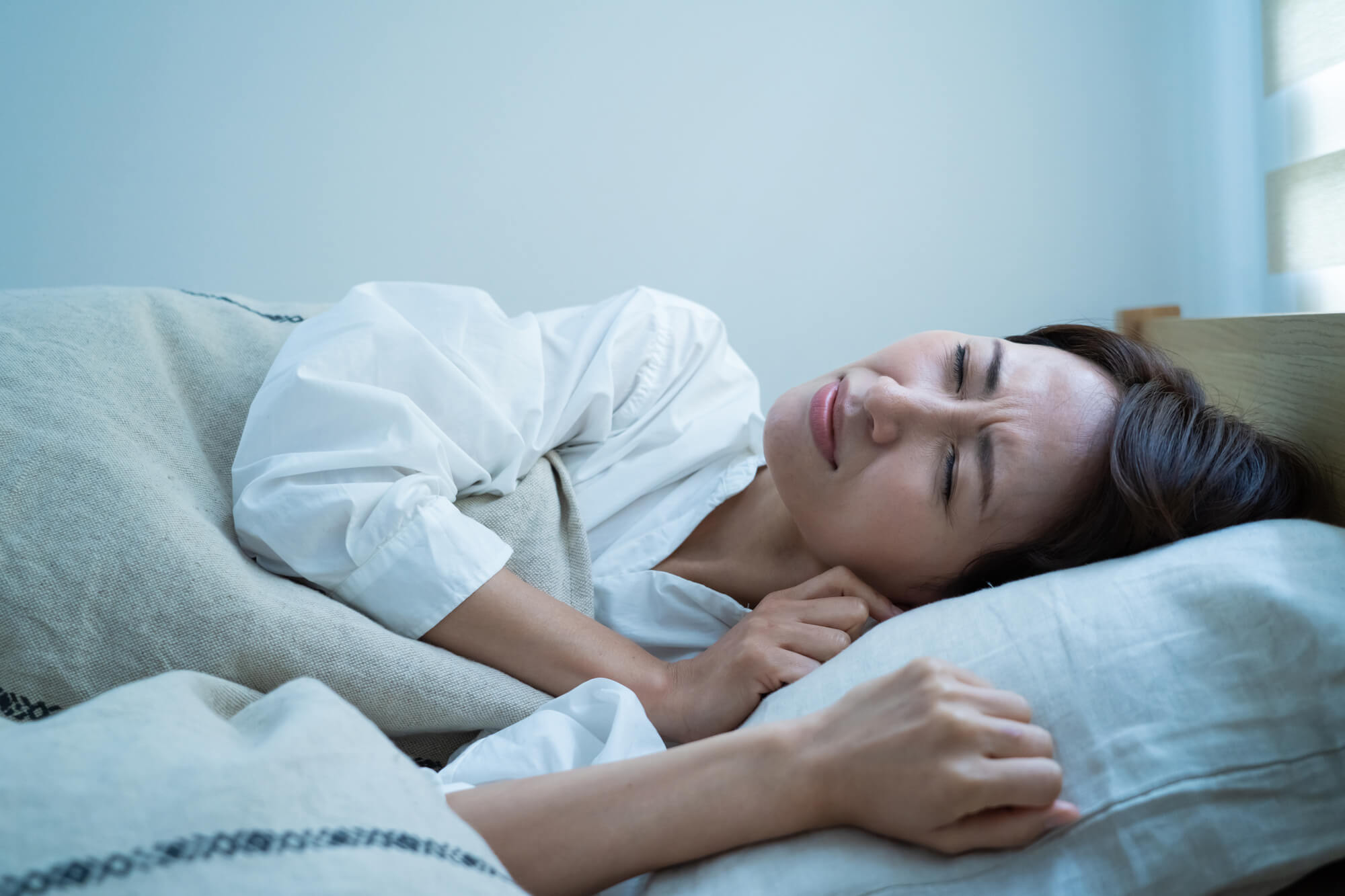 眉間にしわを寄せ寝苦しそうな女性